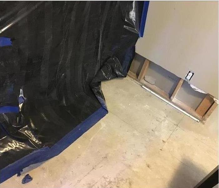 black sheeting plastic, cleaned floor and opened wall visible