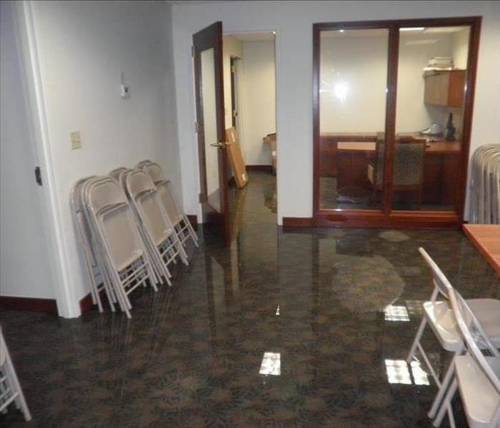 pooling water on carpeted office area, chairs stacked against wall