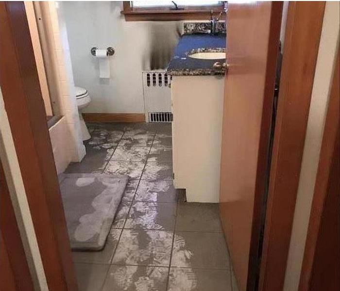 sooty deposits on tiled floor and bathroom fixtures